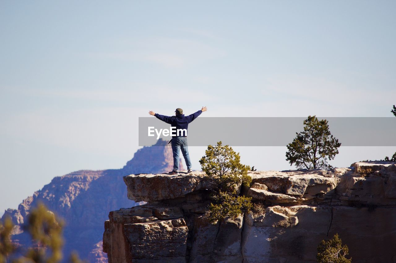 Man standing on rock against sky