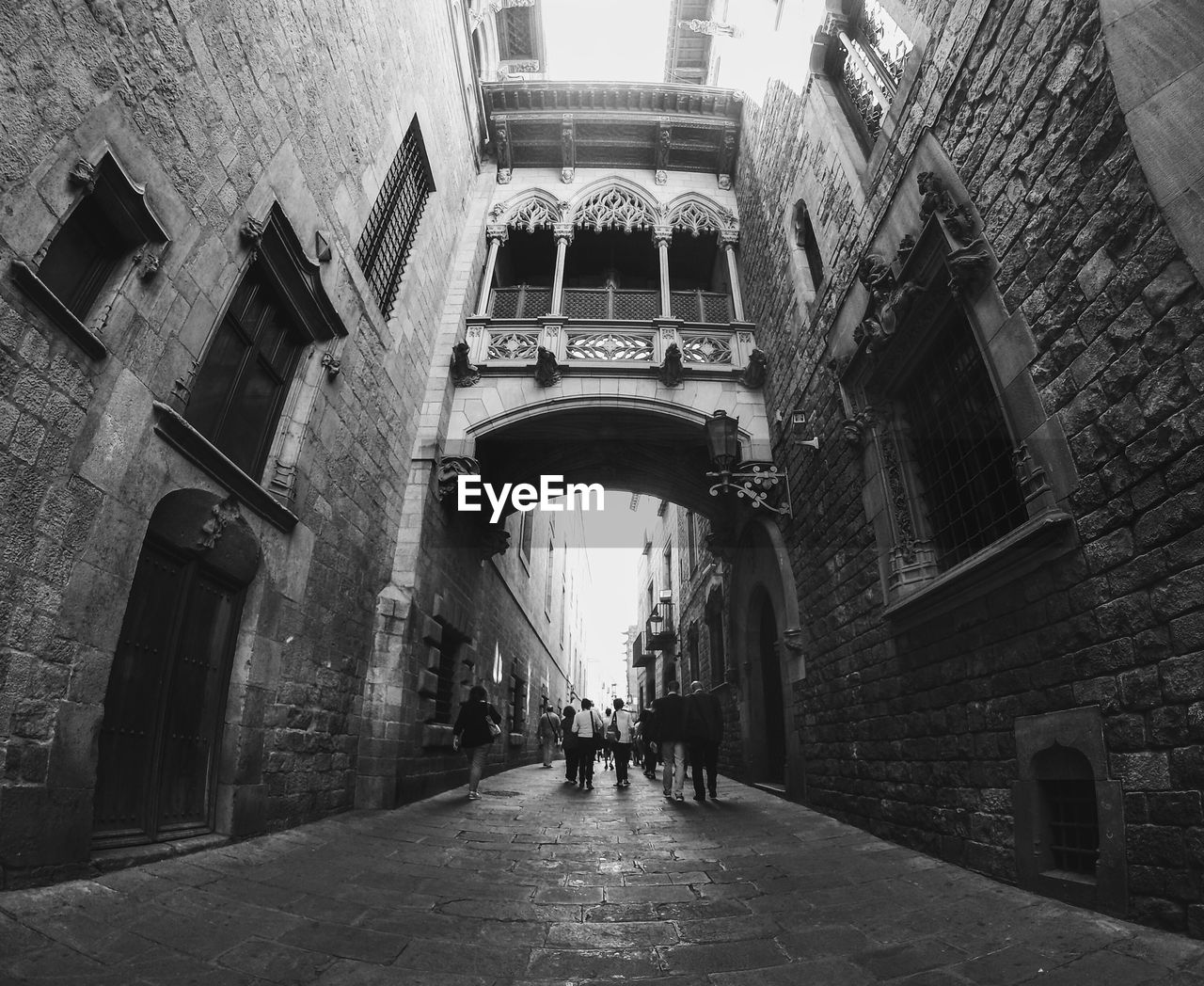 Fish-eye view of people walking in alley amidst buildings