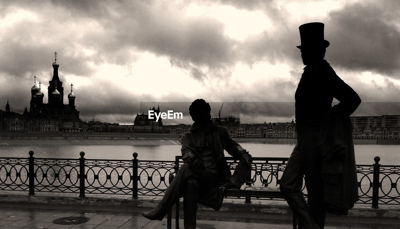 REAR VIEW OF MAN AND WOMAN STANDING AT SEASIDE