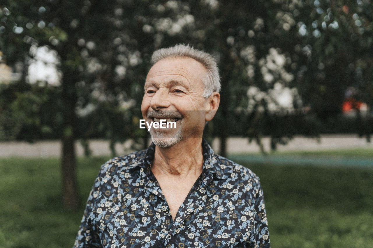 Happy senior man looking away at park