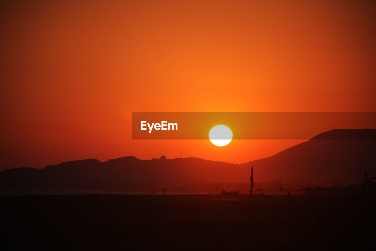 Scenic view of silhouette mountains against orange sky