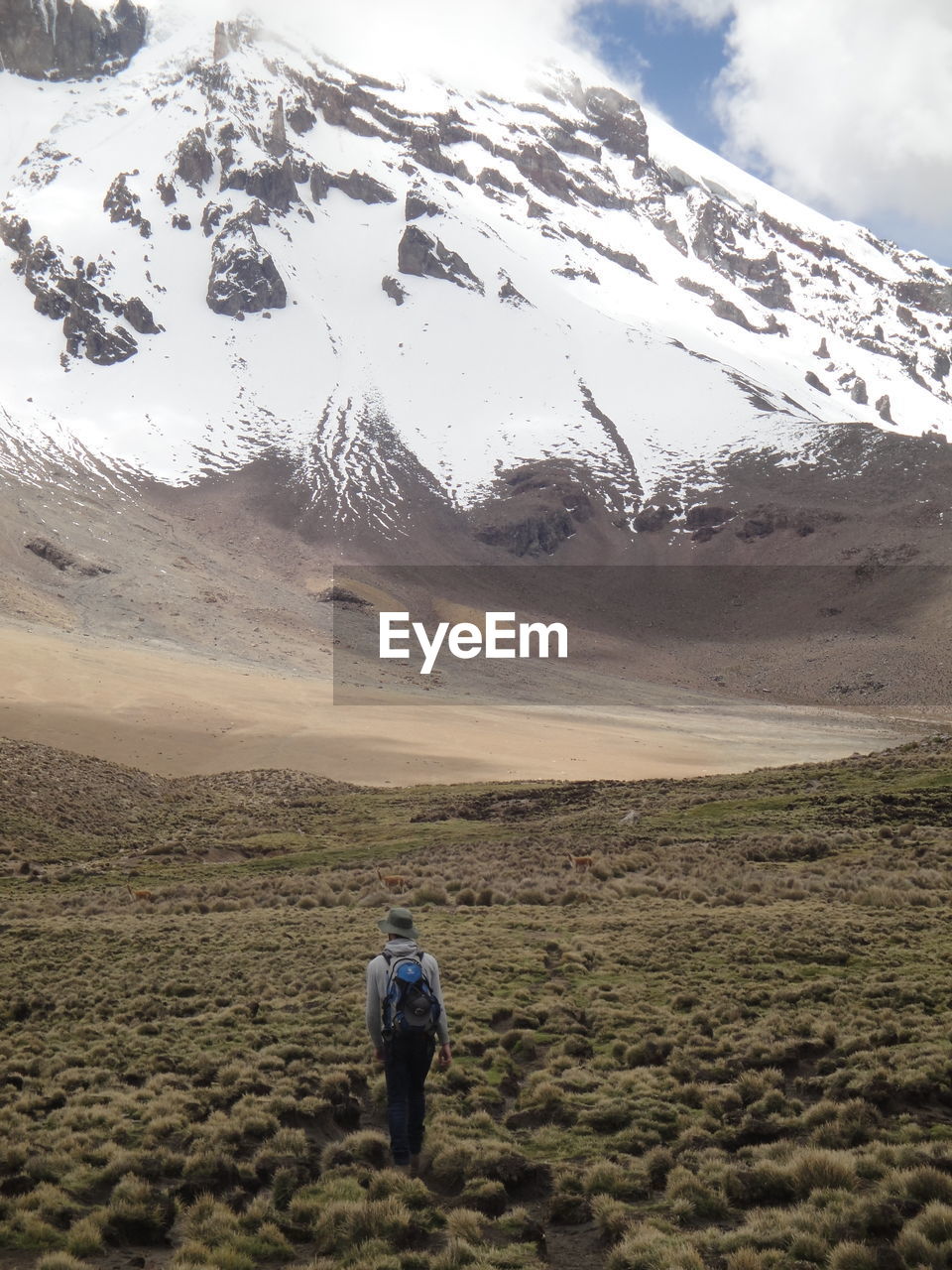 Rear view of woman walking towards snowcapped mountain during winter
