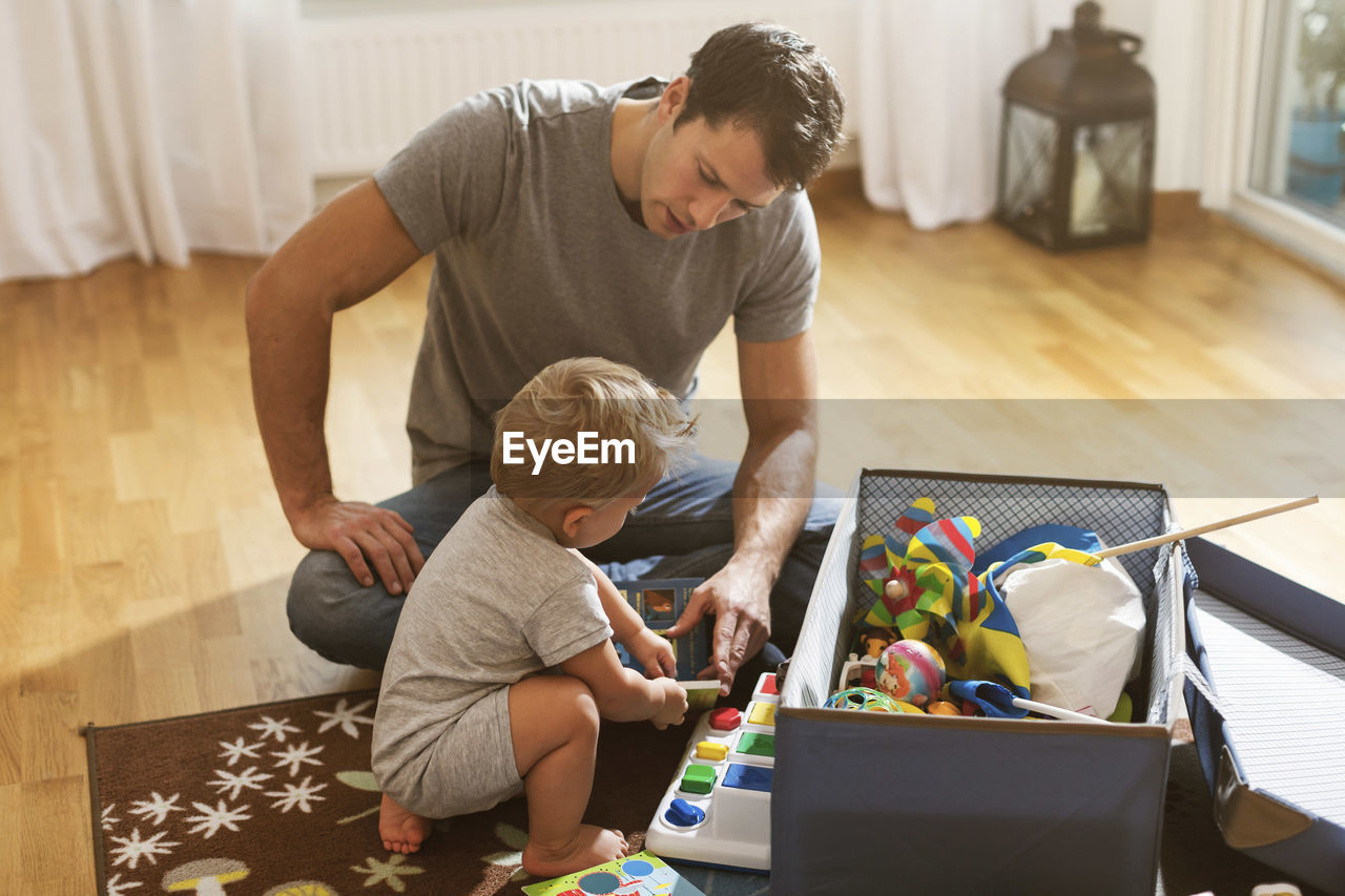 Father and baby boy playing toys on floor at home