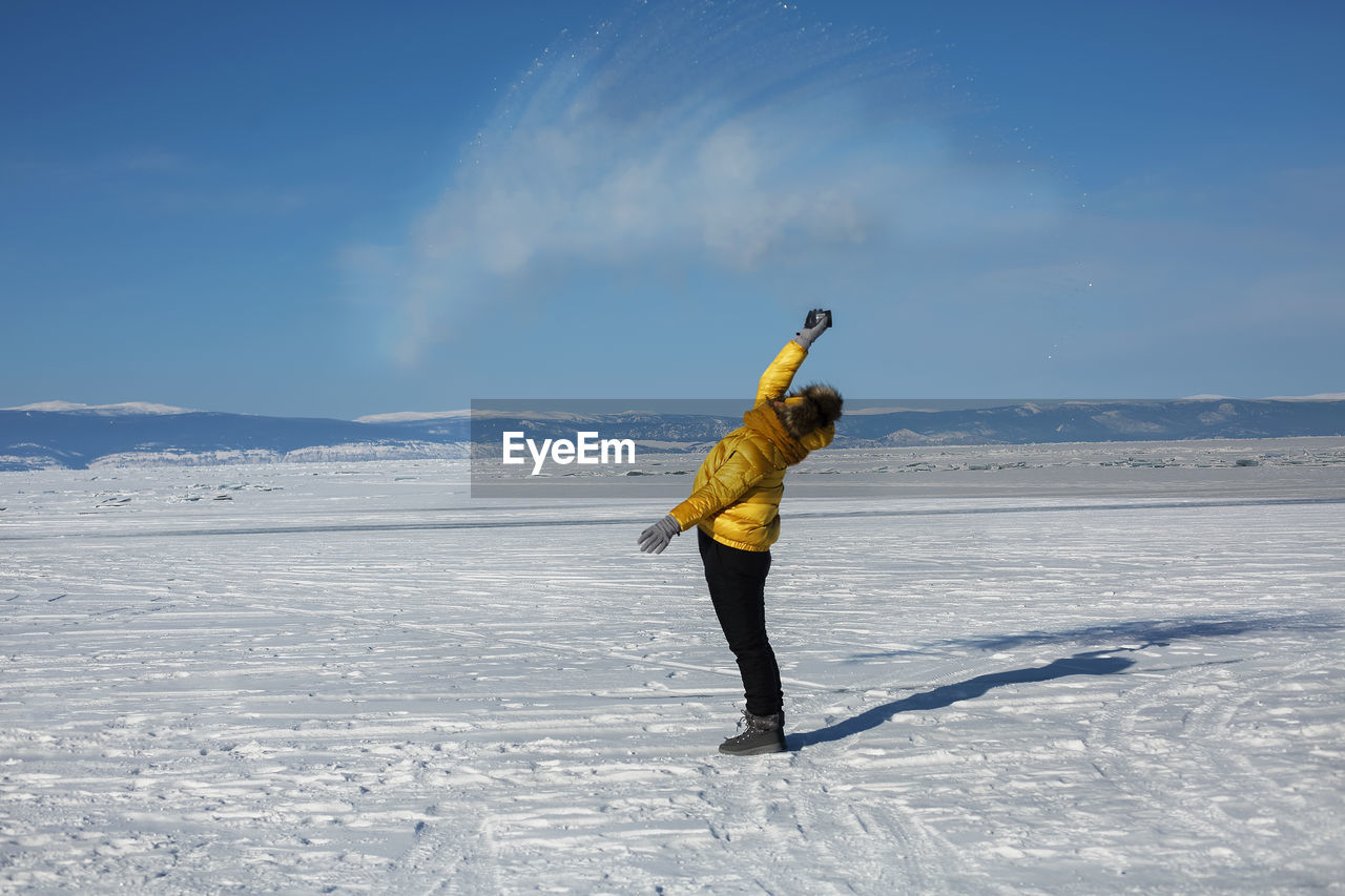 full length of man standing on snow covered landscape against sky