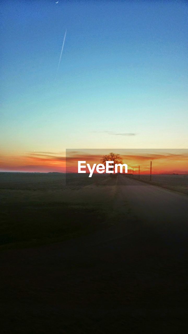 Road on field against orange sky