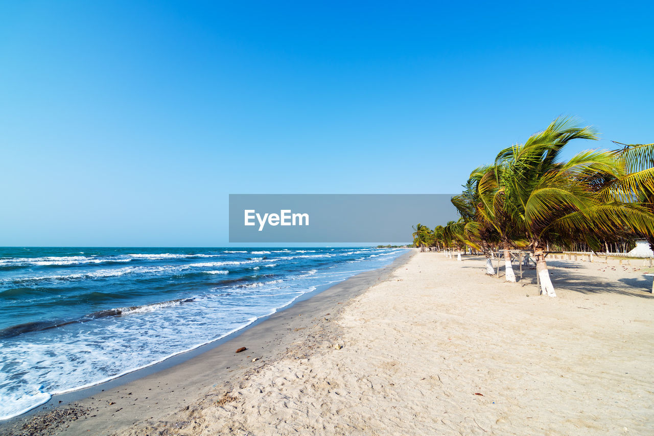 Scenic view of beach against clear blue sky