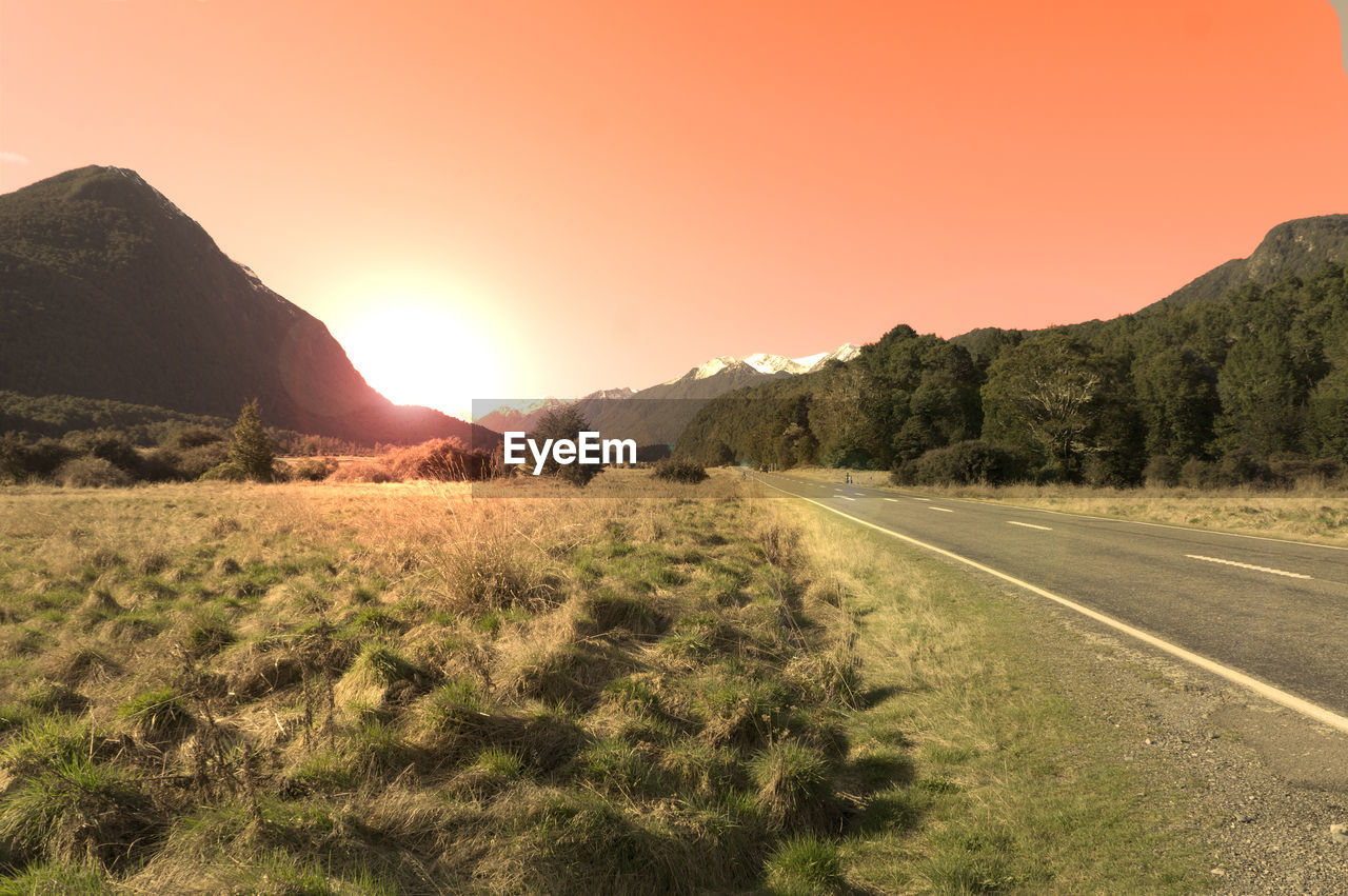 ROAD BY LANDSCAPE AGAINST CLEAR SKY DURING SUNSET