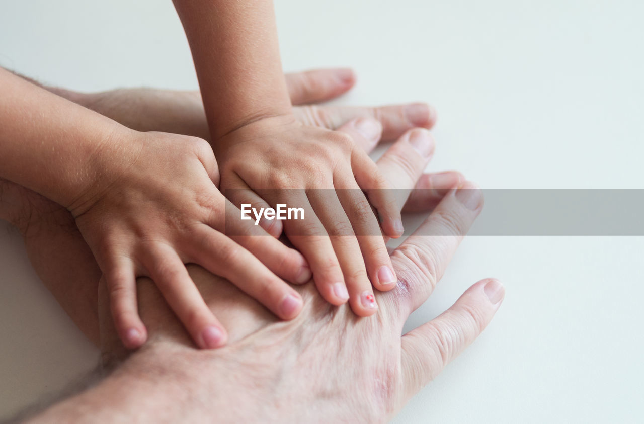 Cropped image of family hands stacking on white table