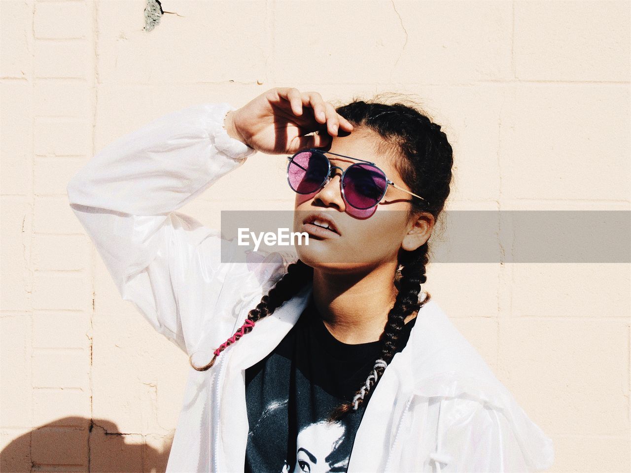 Young woman wearing sunglasses against wall