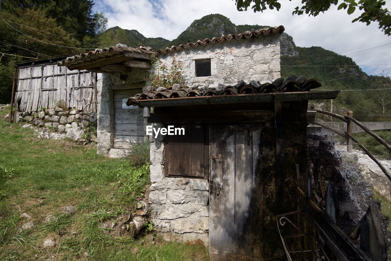 OLD ABANDONED BUILDING BY TREE MOUNTAIN AGAINST SKY