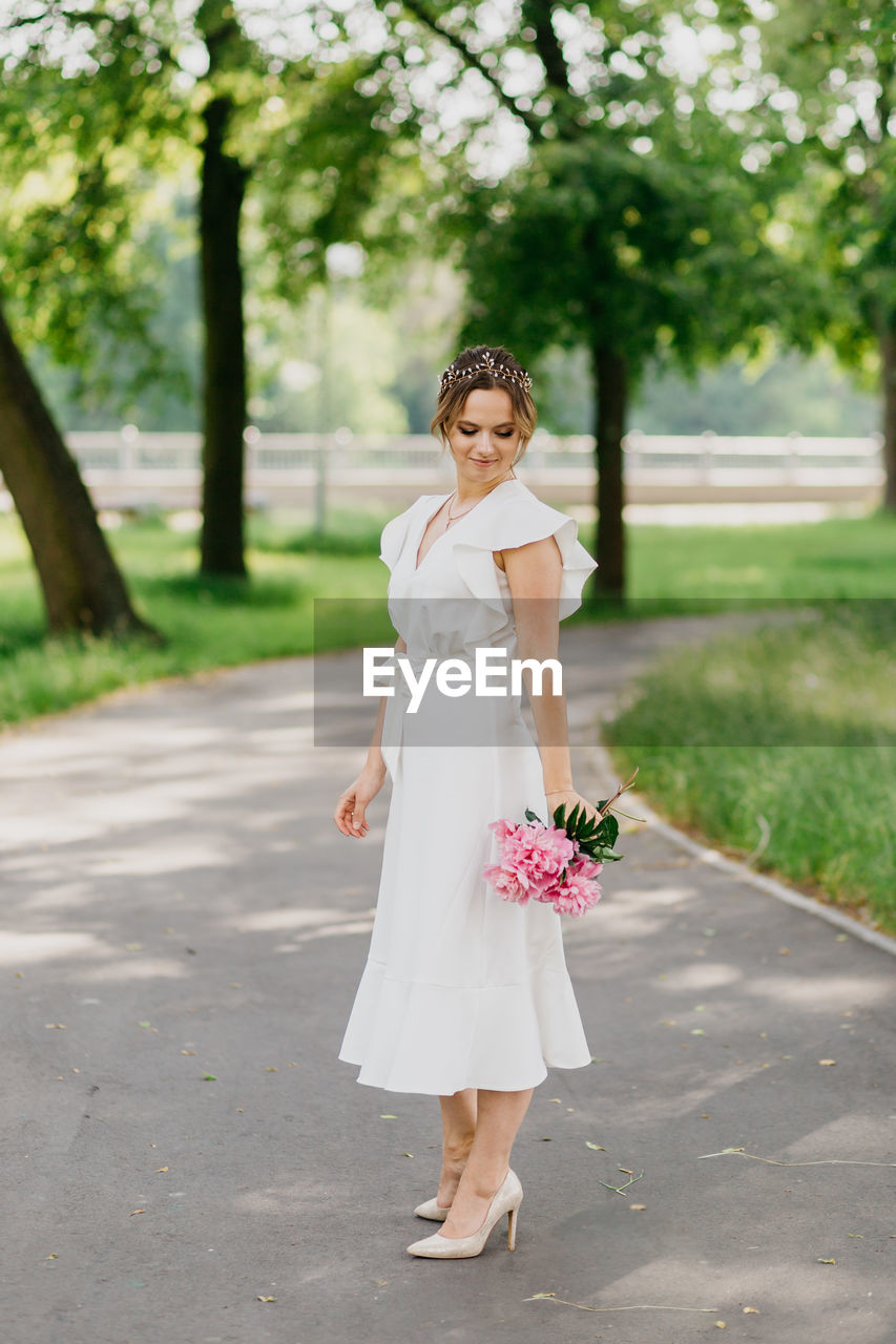 Full length of woman standing holding bouquet in park