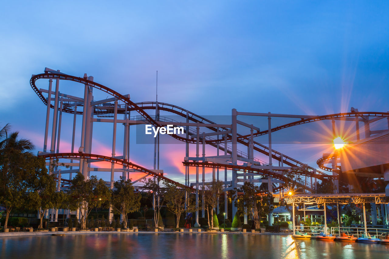 LOW ANGLE VIEW OF ILLUMINATED FERRIS WHEEL AT SUNSET