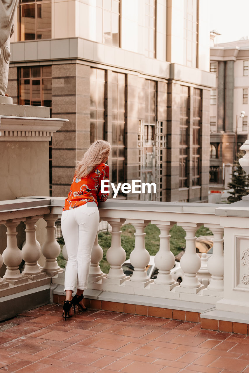 Girl on the street terrace looks, rear view. blonde girl in europe on the balcony