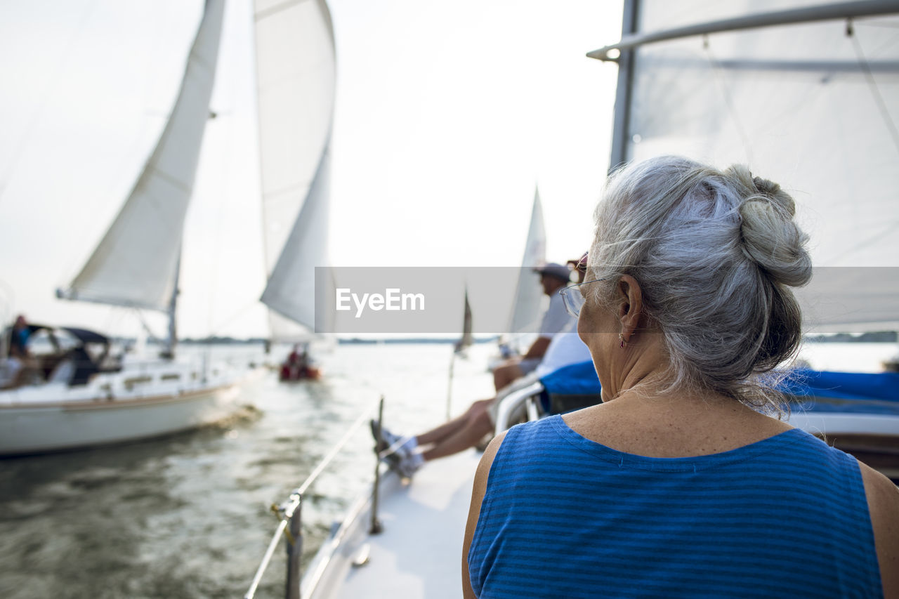 Middle aged woman enjoying summer sail race during golden hour