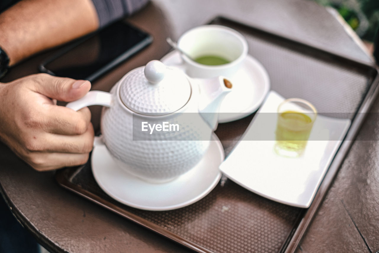 MIDSECTION OF WOMAN HOLDING COFFEE CUP AND TABLE