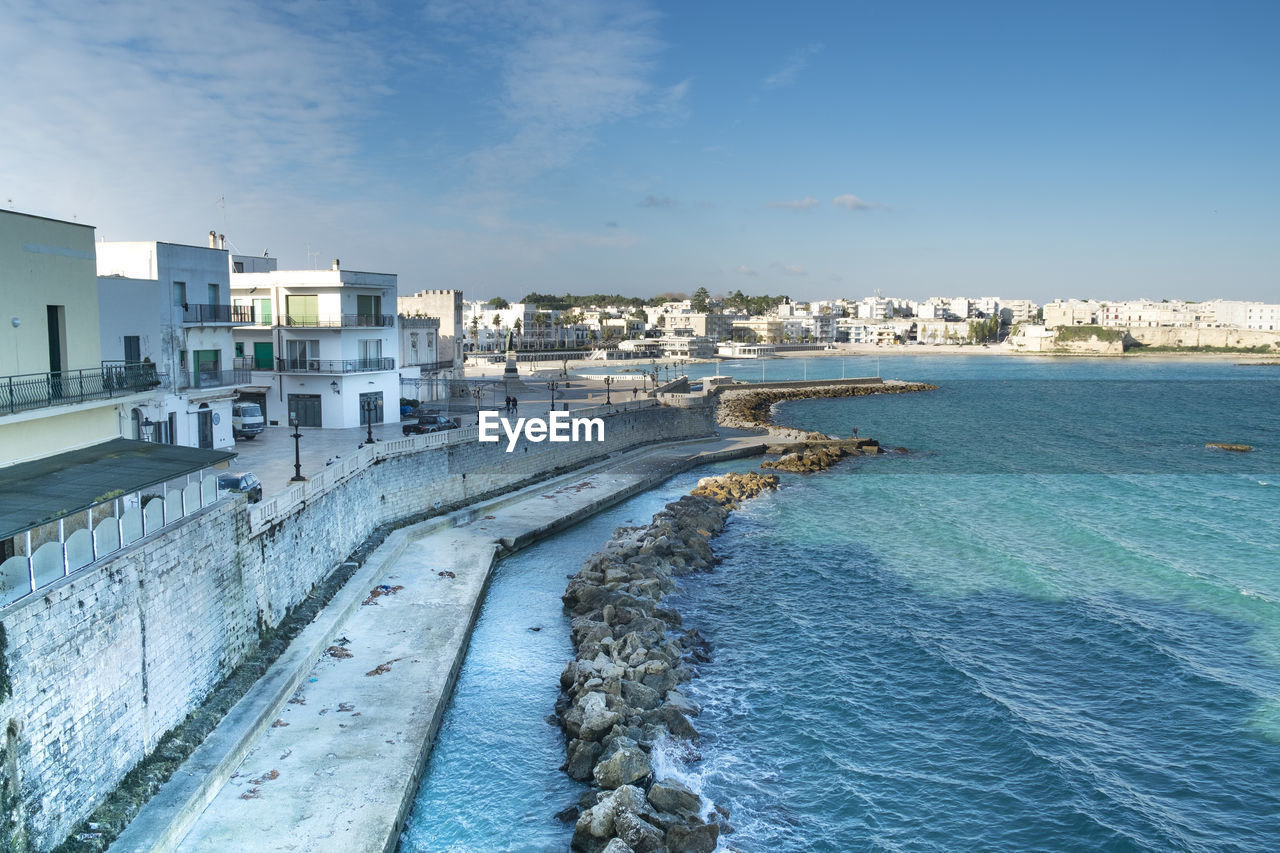Buildings by sea against sky