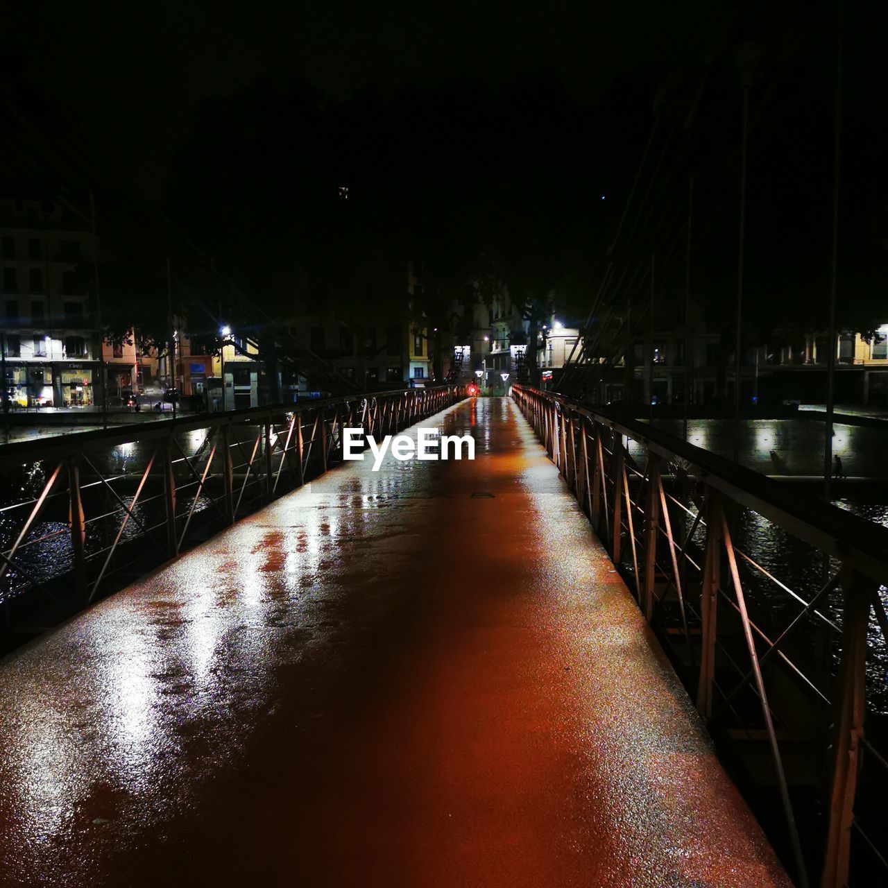 ILLUMINATED BRIDGE OVER CANAL AT NIGHT