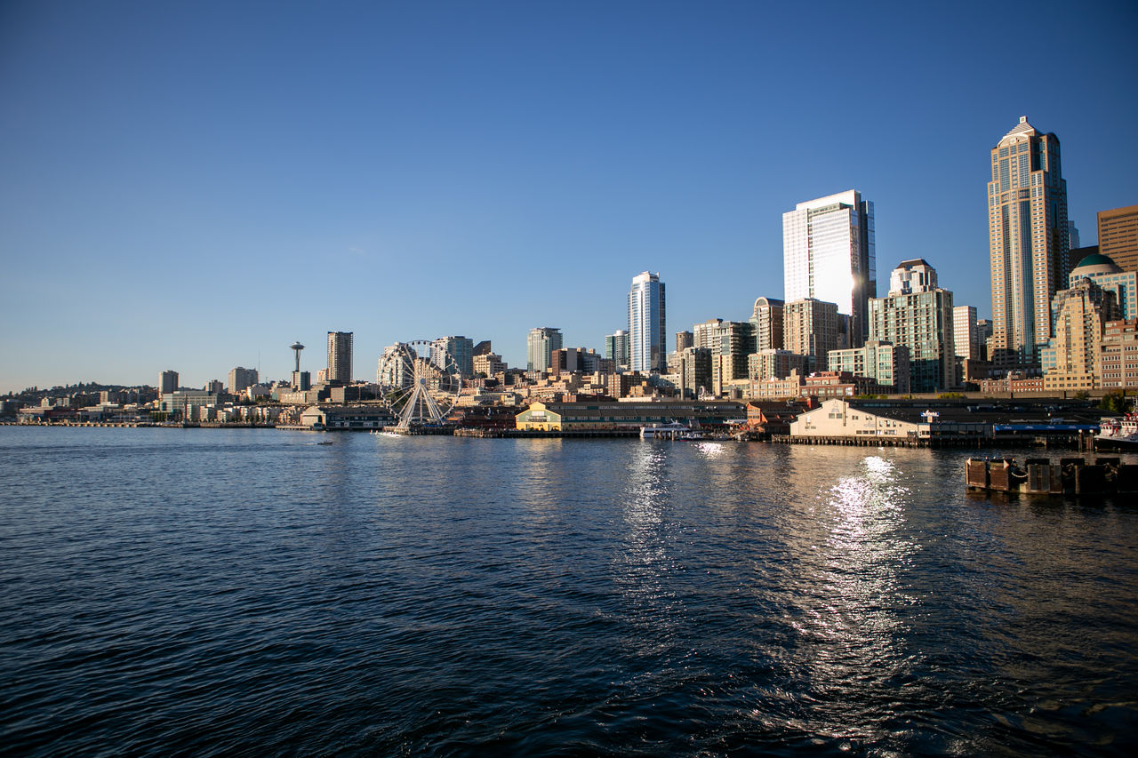 Sea by city buildings against clear sky