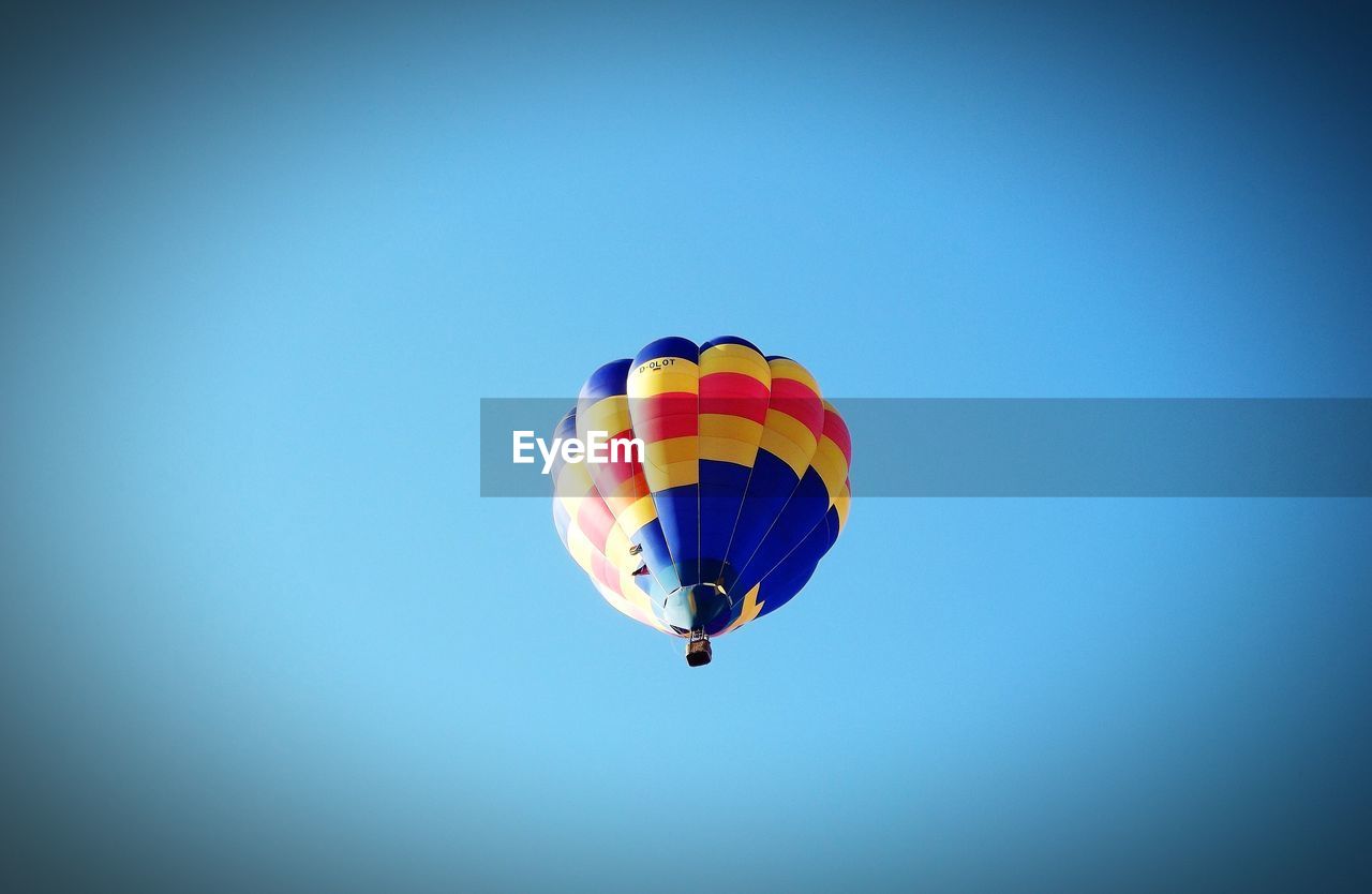 Low angle view of hot air balloon flying against clear blue sky