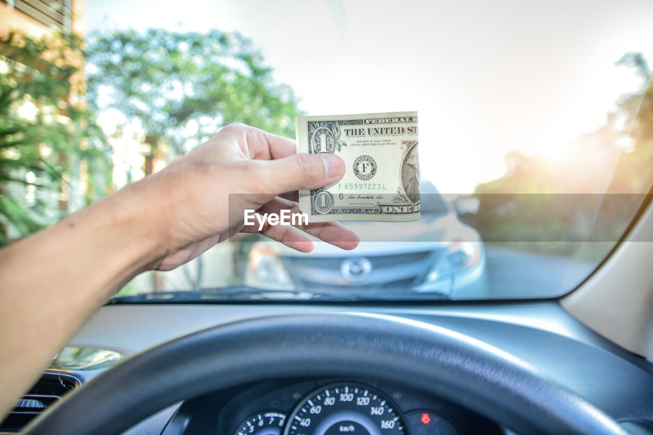 Cropped hand of man holding paper currency in car