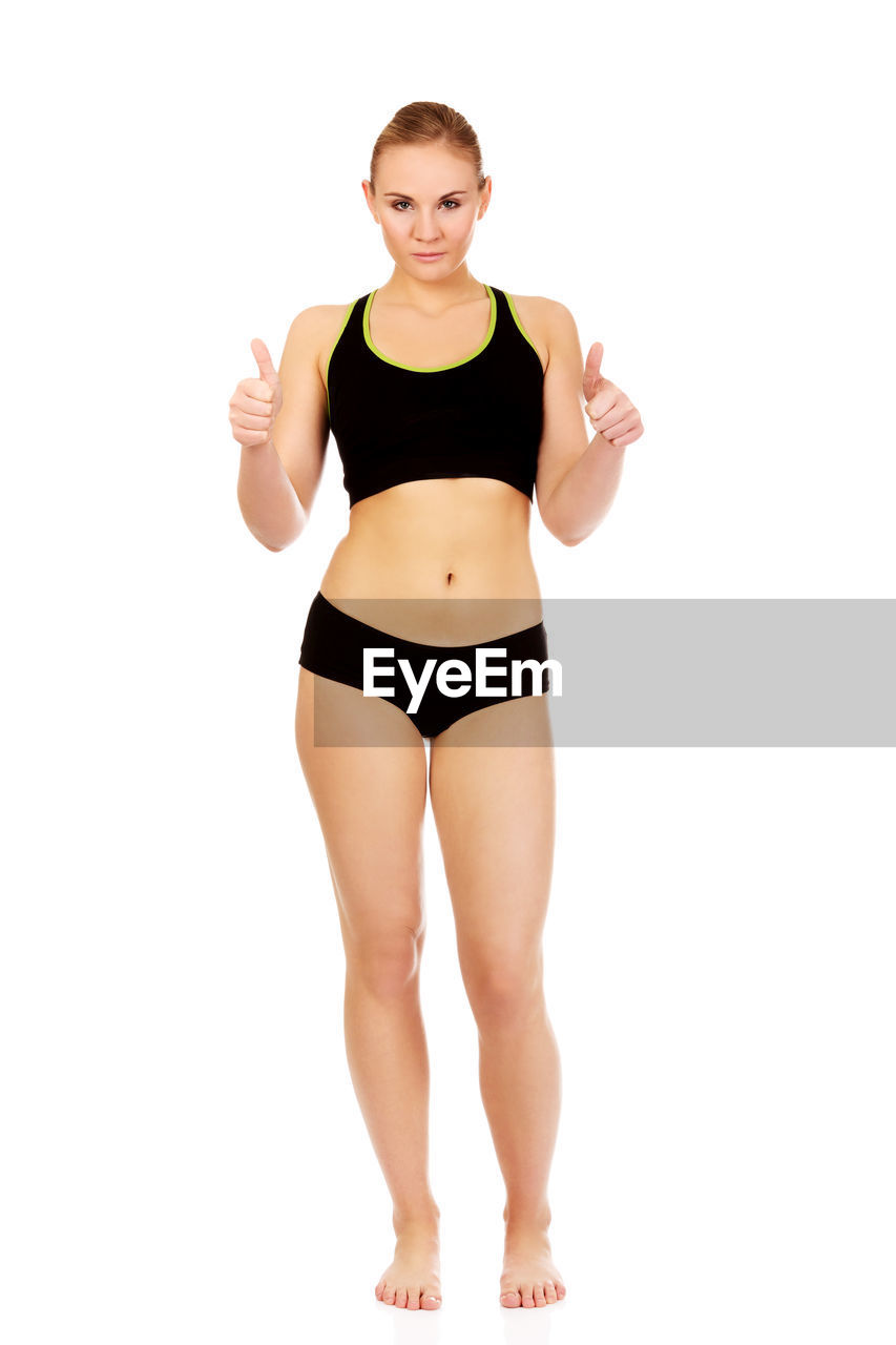Portrait of young woman in sports clothing gesturing against white background