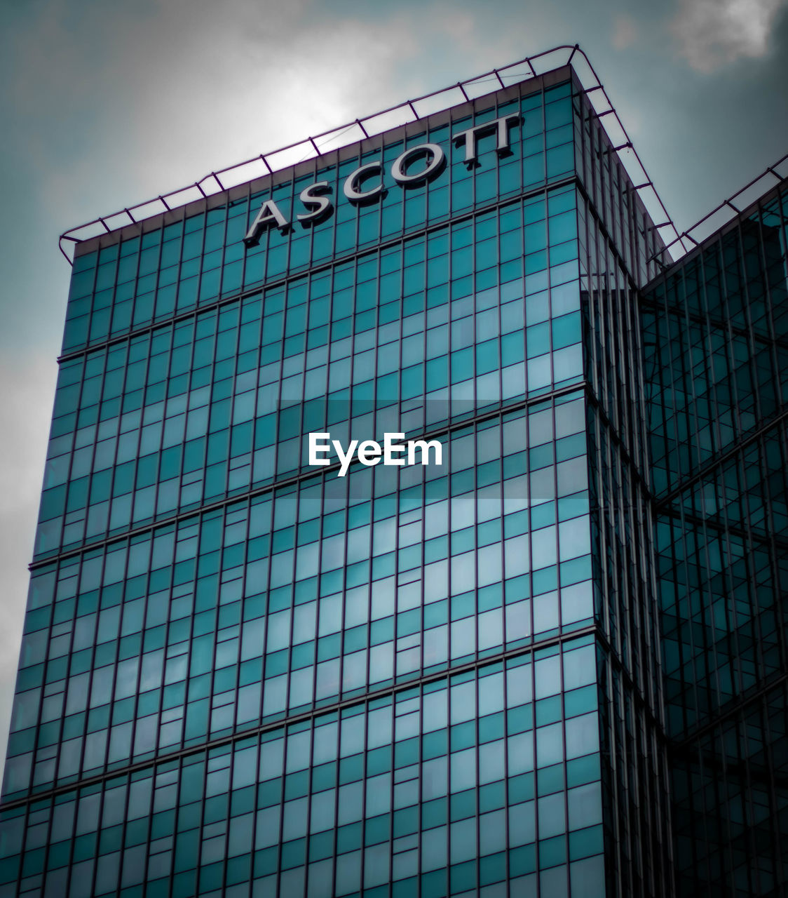 LOW ANGLE VIEW OF MODERN GLASS BUILDING AGAINST SKY