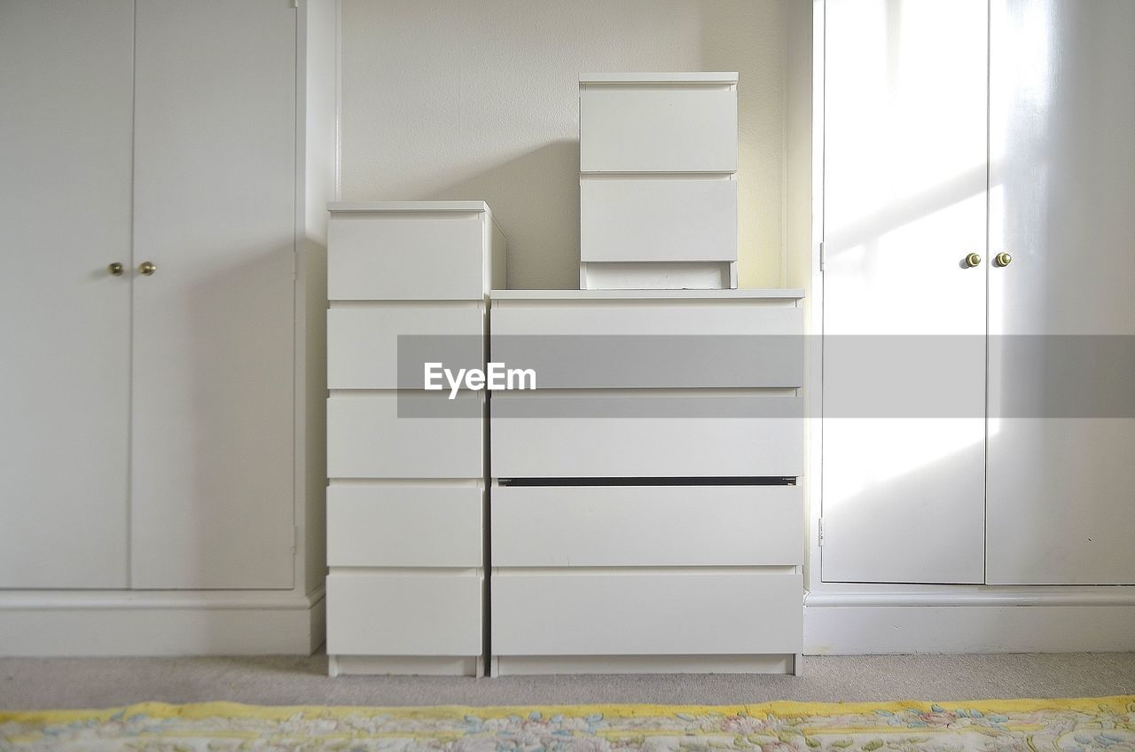 Stack of white boxes amidst closets against wall at home