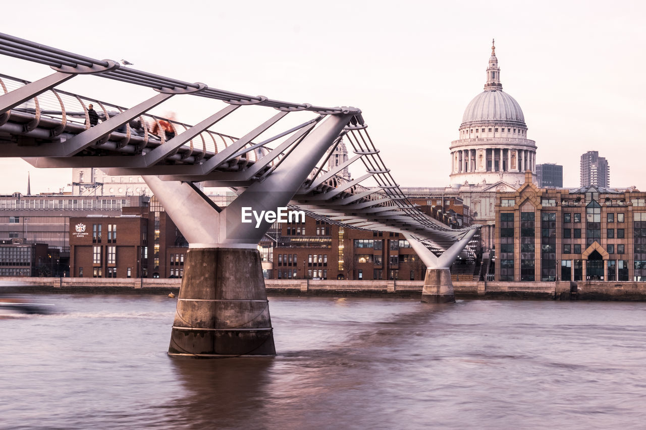 Low angle view of bridge over river by historic building against sky