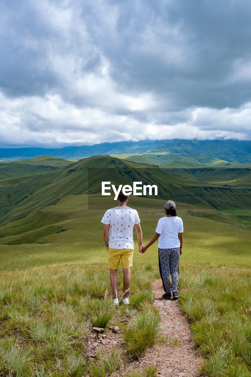 Rear view of couple standing on grass against sky