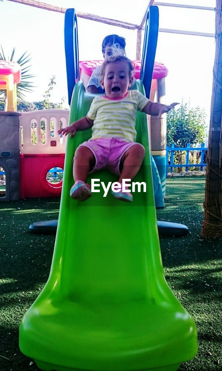 Low angle view of frightened girl on slide at park