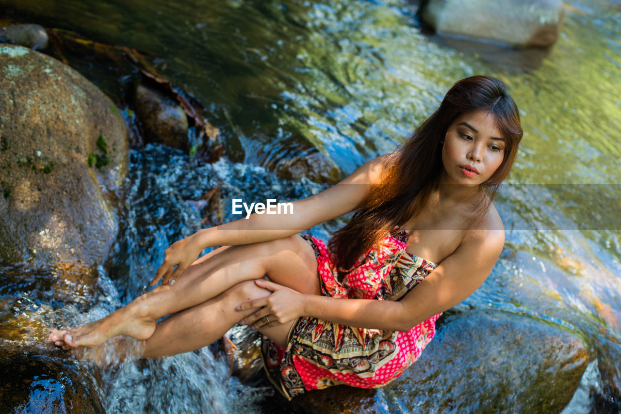 High angle view of thoughtful young woman sitting in river