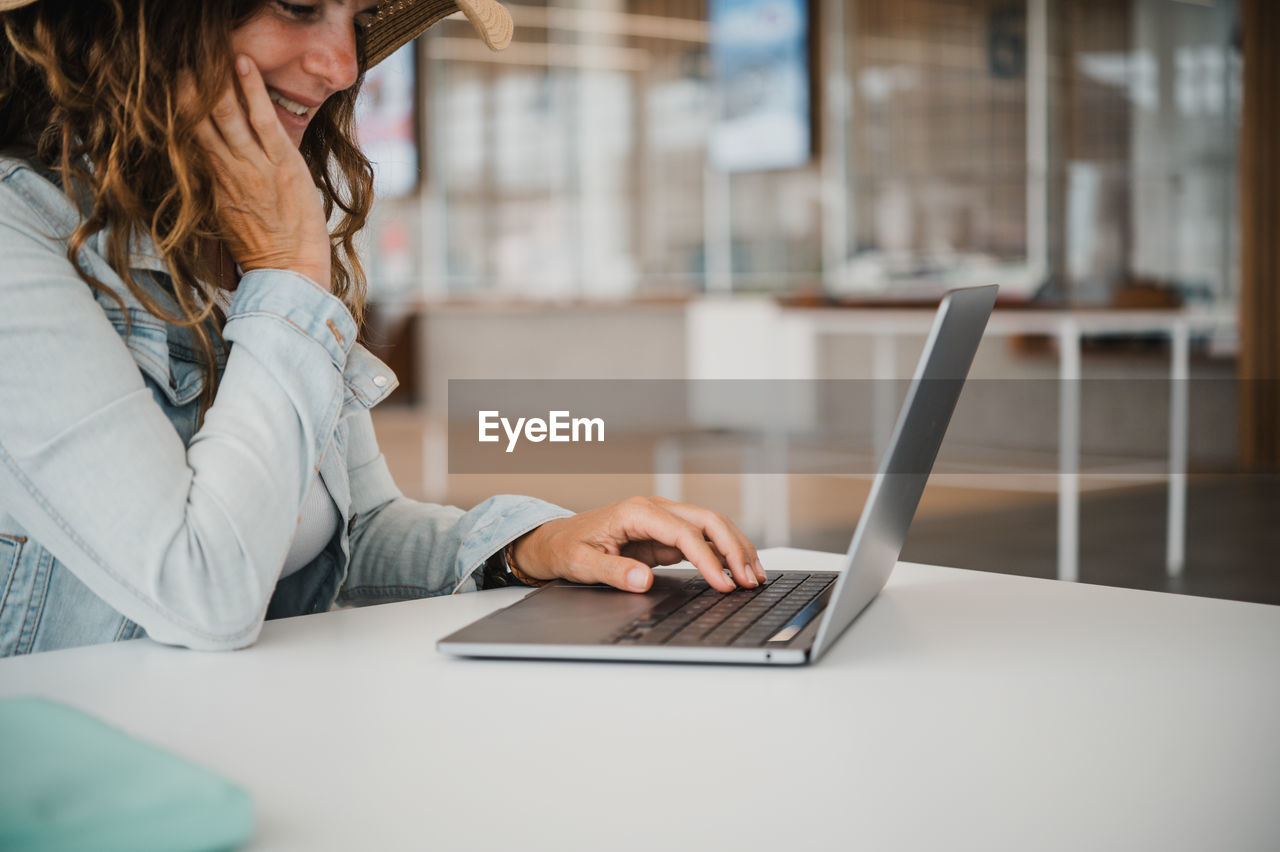 midsection of businesswoman using laptop at table