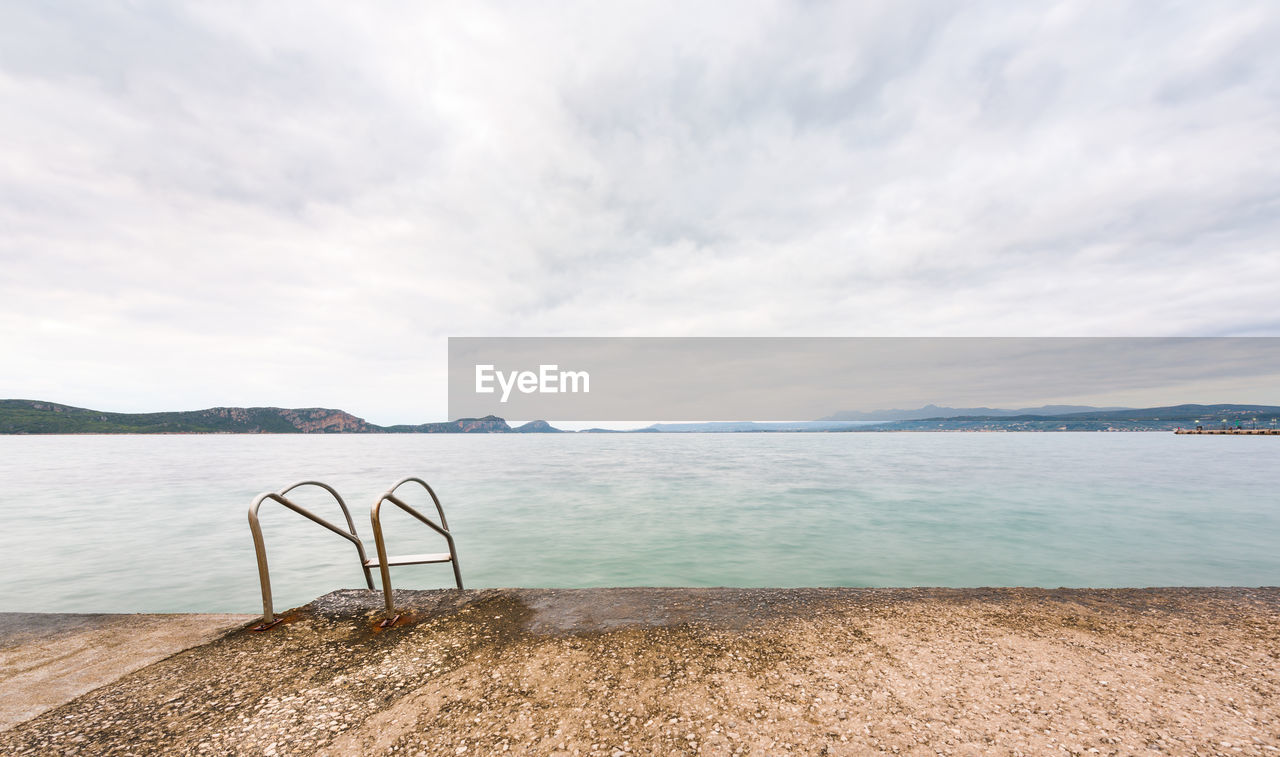 Overcast seascape from a jetty with swimming pool ladder plungeing in to the sea in pylos, greece