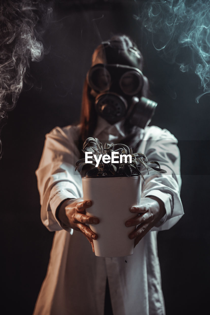 Midsection of young woman wearing mask against black background