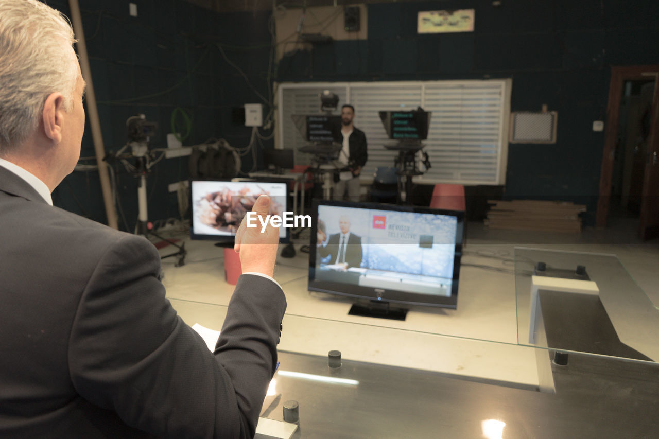 REAR VIEW OF MAN WORKING IN OFFICE