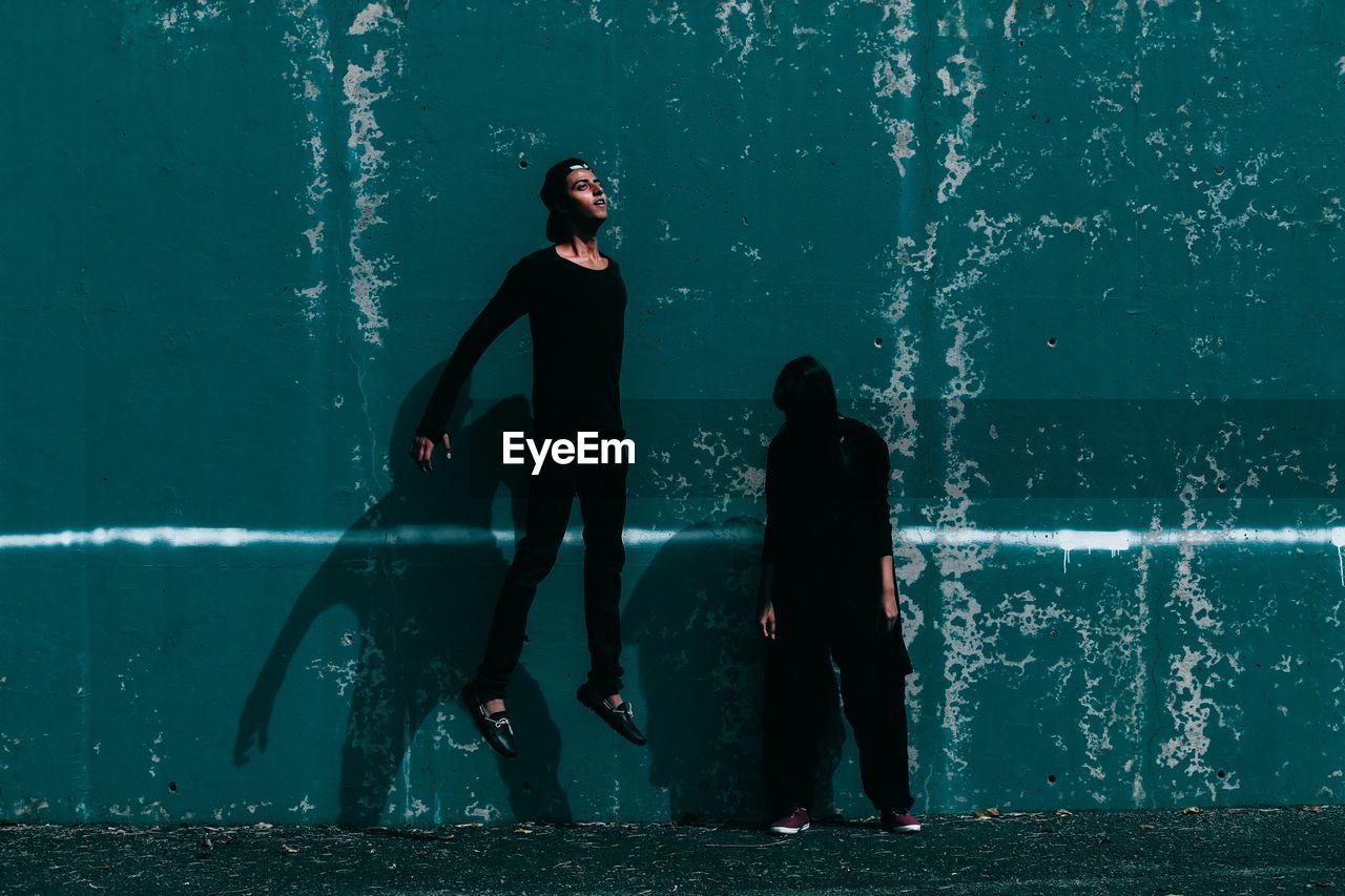 Man in mid-air while woman standing against wall