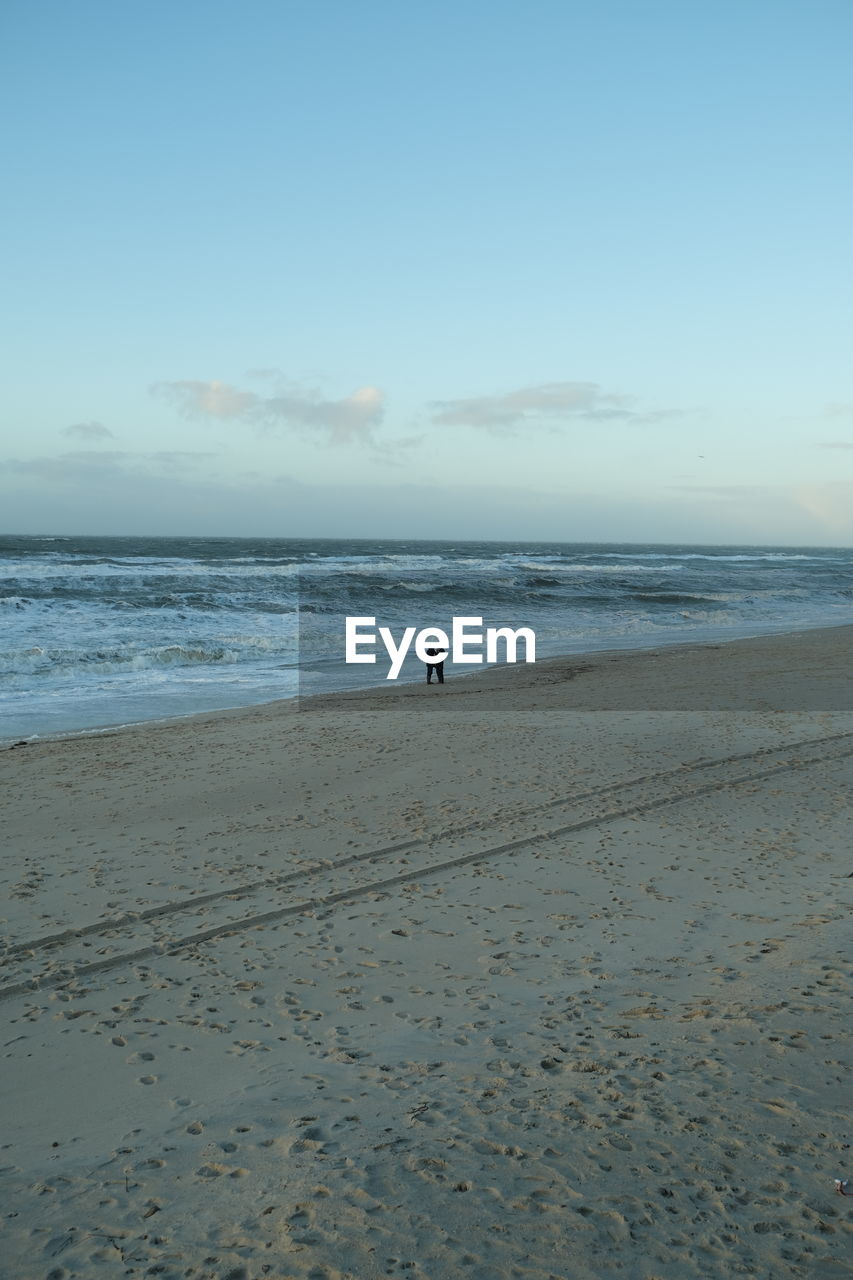 Scenic view of couple walking by the sea against sky