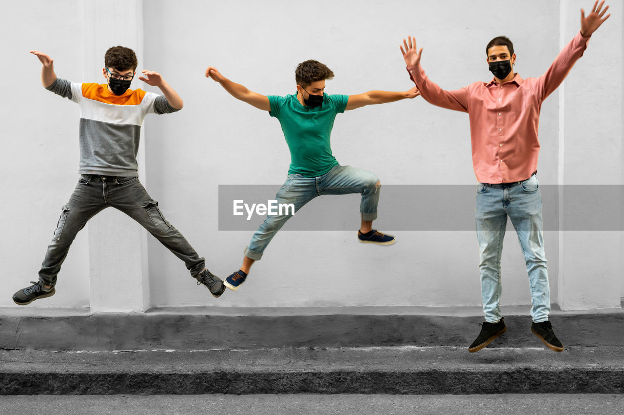 Full length of young man jumping against wall