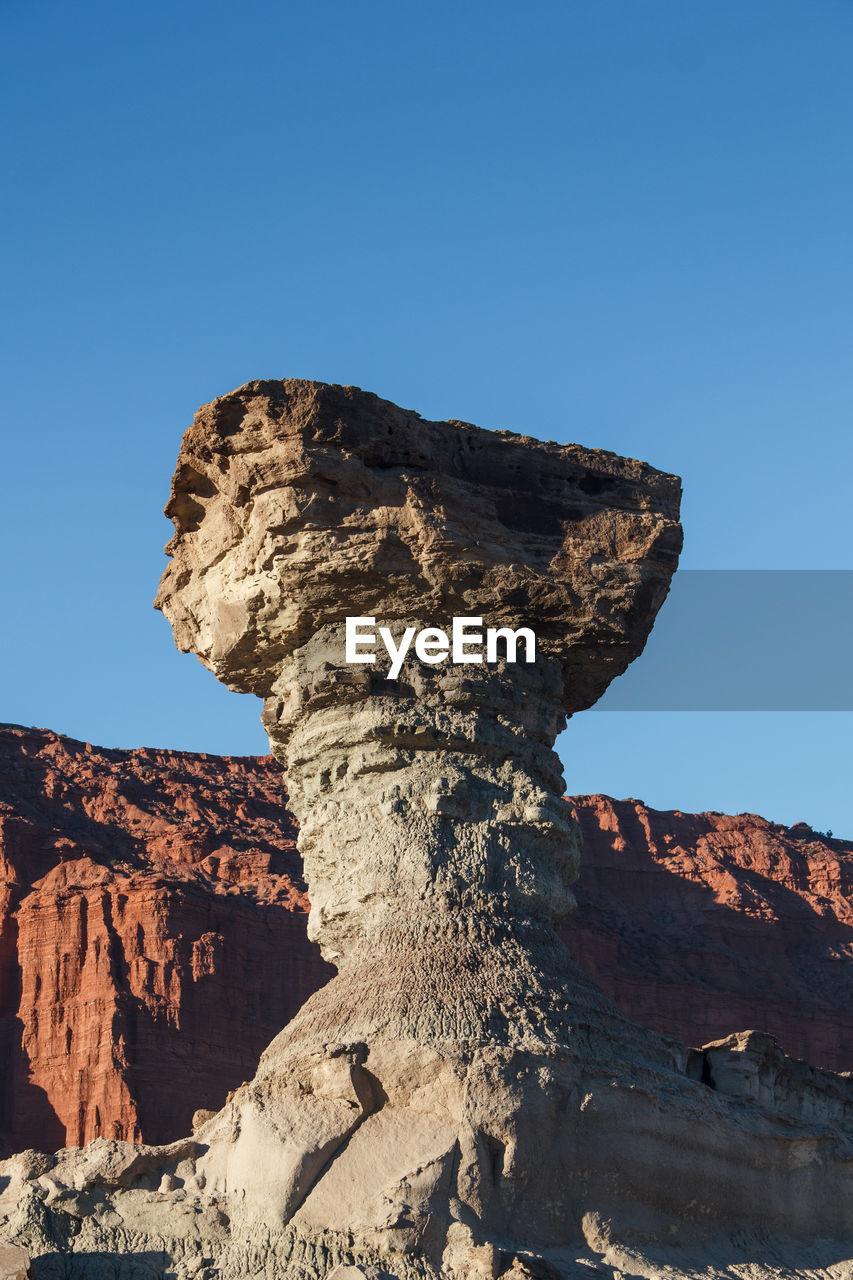 Low angle view of rock formation against clear blue sky