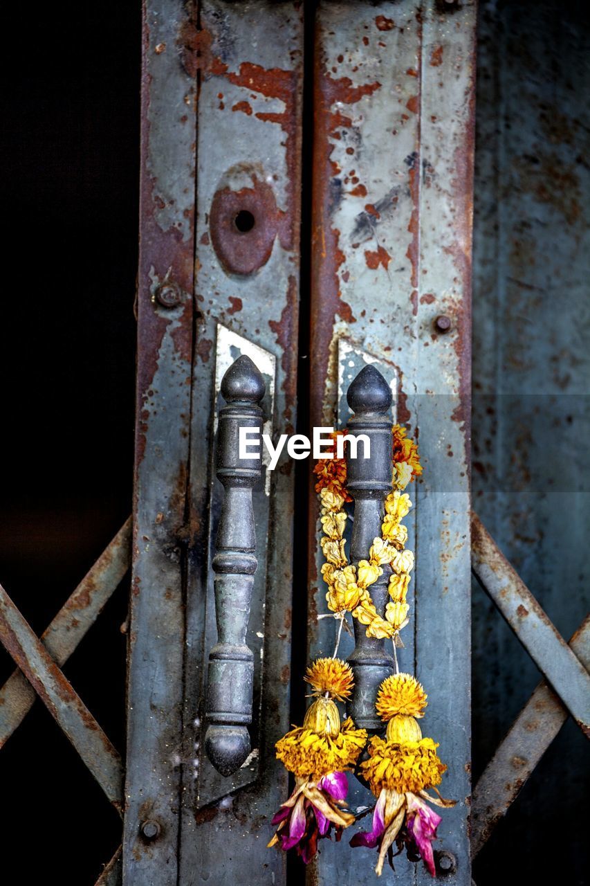 Close-up of garland hanging on handle of closed metal door