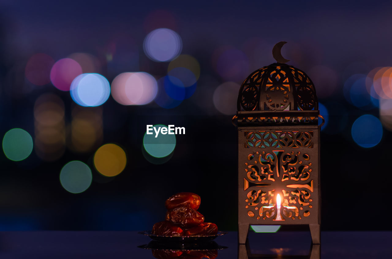 Lantern and small plate of dates fruit with night sky for the holy month of ramadan kareem.