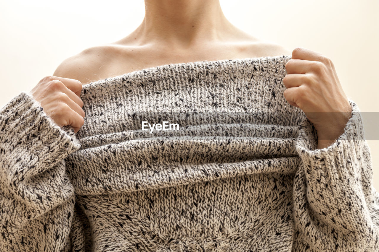 Midsection of woman in sweater against white background