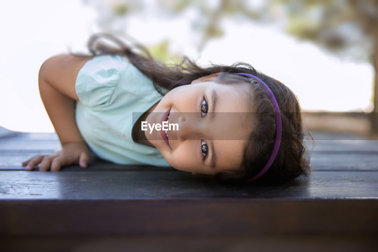 Portrait of smiling girl lying on table