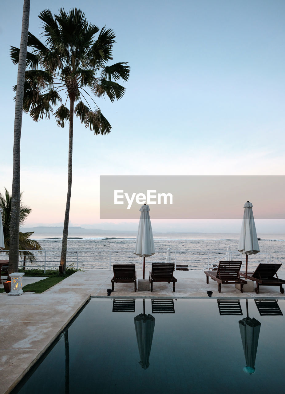 Still pool and deckchairs at a luxury resort at sunset 