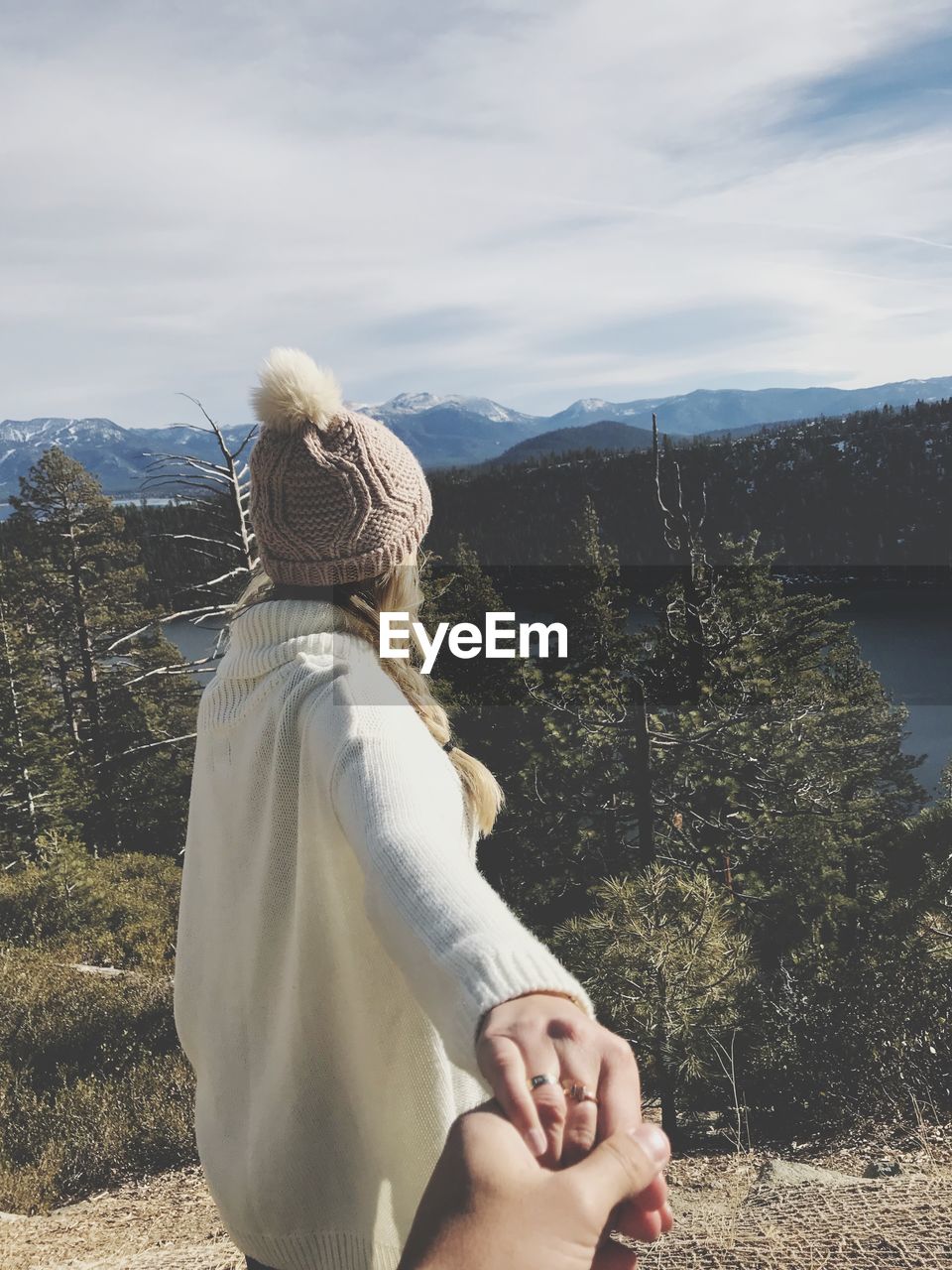 Cropped image of man holding hands with girlfriend against mountains