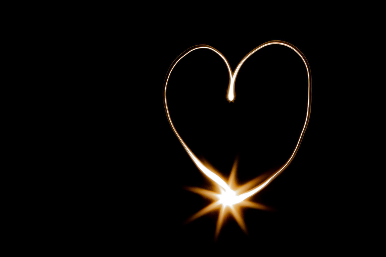 Heart shape light painting with lens flare against black background