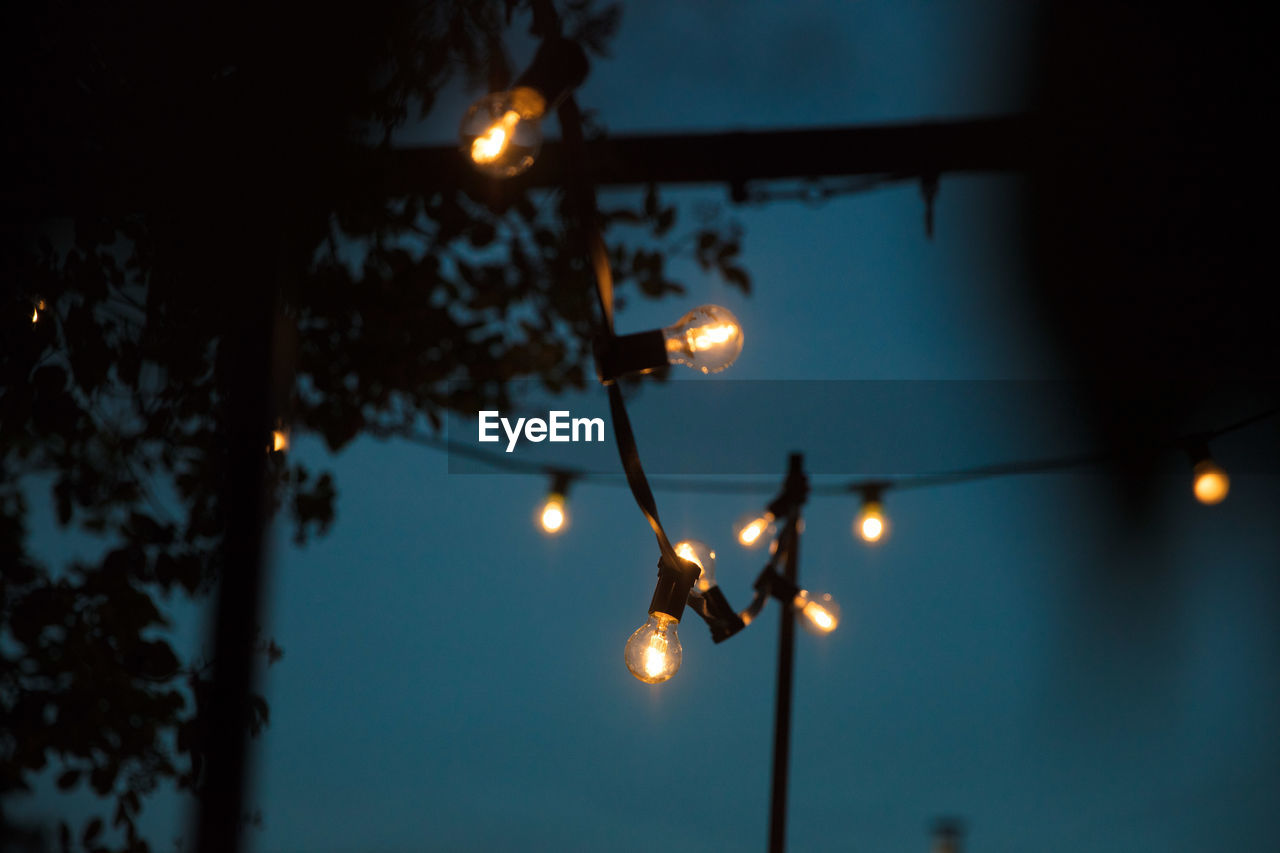 Low angle view of illuminated string light against sky at night