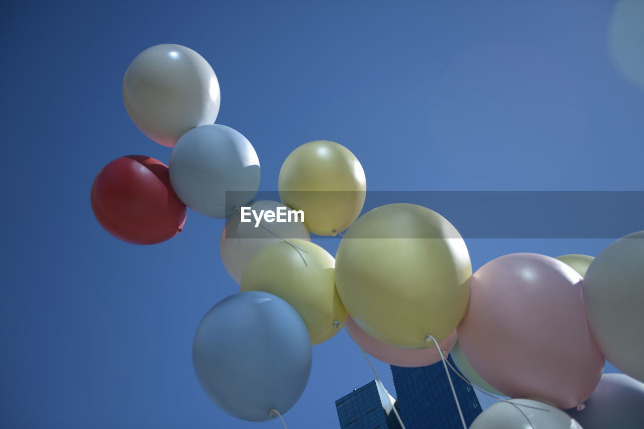 LOW ANGLE VIEW OF BALLOONS IN BLUE SKY