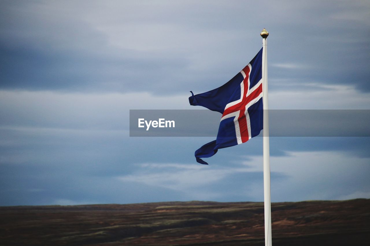 Low angle view of icelandic flag on pole against sky