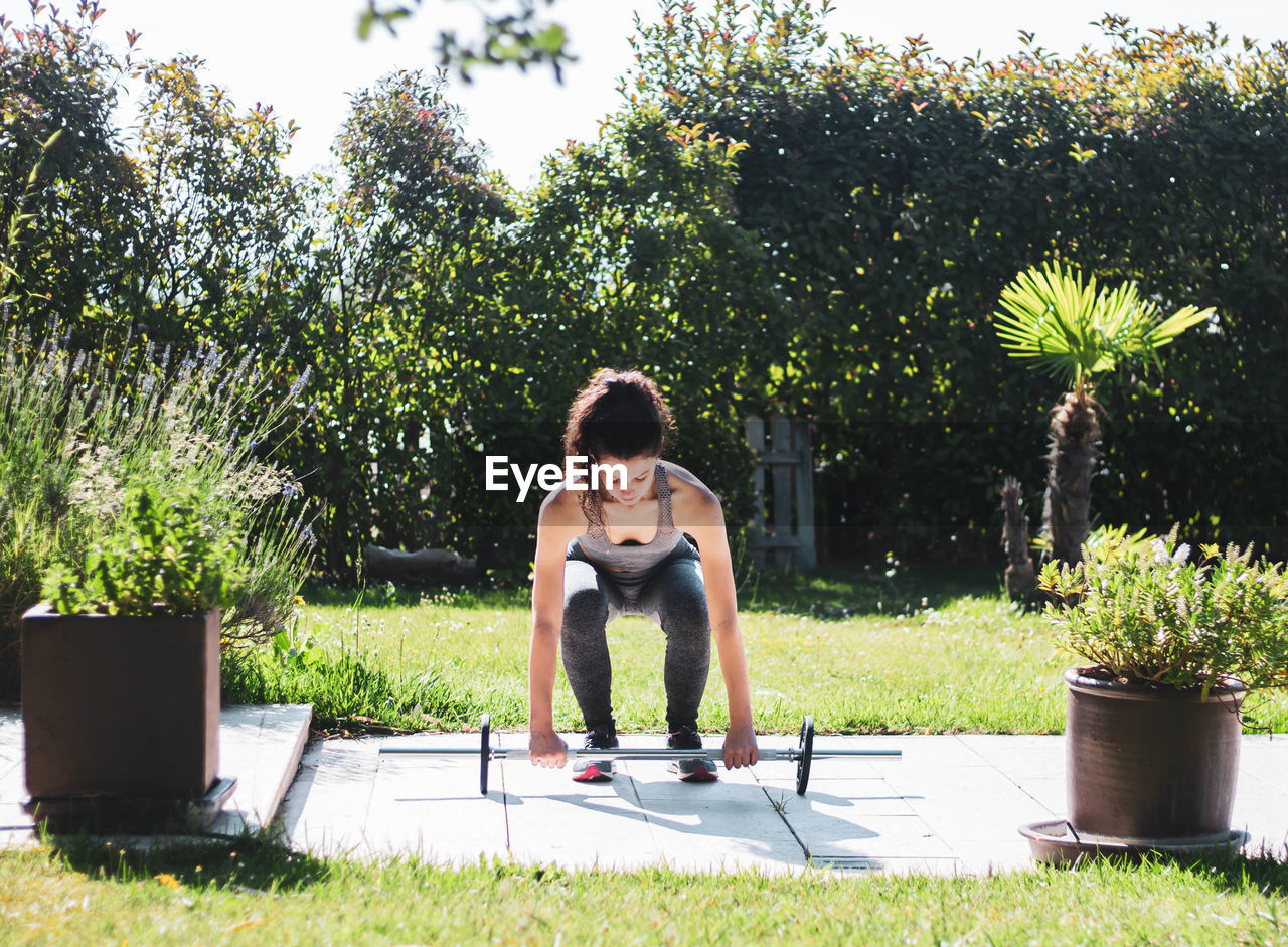 Young woman exercising in her home garden